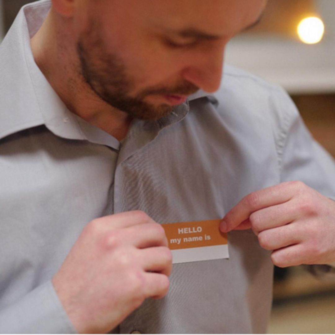 middle aged male putting badge with name on his shirt